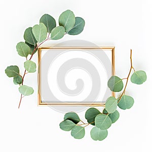 Gold frame is decorated with green branches and eucalyptus leaves on a white background. lay flat, top view