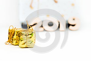 Gold gift boxes and symbol numbers 2019 new year on white background, simple flatlay card of new year. Selective focus