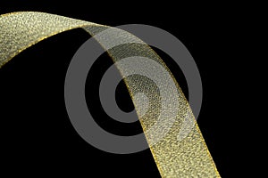 Gold gift wrap ribbon on black fabric background. Holiday, gold fabric ribbon on black background. With copyspace