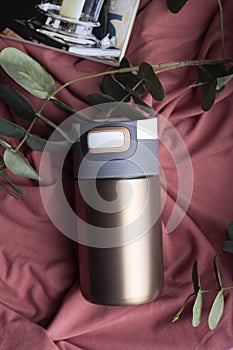 Gold glass beaker glass refrigerator. Stainless steel thermos mug isolated on brown background. photo