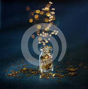 Gold glitter confetti in the small glass bottle. Close up on classik blue  background