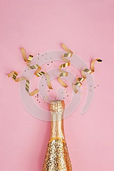 Gold glittering bottle of champagne and swirls on pink background