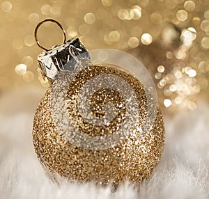 Gold glittering Christmas bauble with a defocused bokeh background and a shallow depth of field