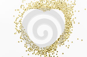 Gold glitters , scattered in disarray lined heart shape isolated on white background with copy space