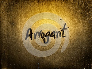 on the gold and grain rough old vintage paper page the word arrogant written by pencil