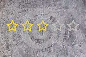 Gold, gray, silver five star shape on the gray concrete background. The best excellent business services rating customer photo