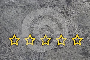 Gold, gray, silver five stars shape on the gray concrete background. Concept image of setting a five star goal. Increase rating or