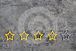 Gold, gray, silver five stars shape on the gray concrete background. Concept image of setting a five star goal. Increase rating or