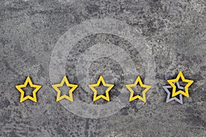 Gold, gray, silver five stars shape on the gray concrete background. Concept image of setting a five star goal. Increase rating or