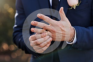 The gold on his finger symbolises commitment. an unrecognizable bridegroom adjusting his ring on his wedding day.