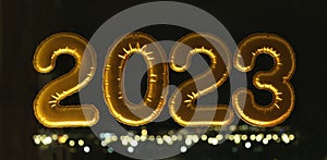 Gold inflatable foil balloons numbers 2023 on the window against the background the night city, in neon light. New year