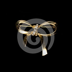 Gold jewelry in the form of a bow with white crystals.