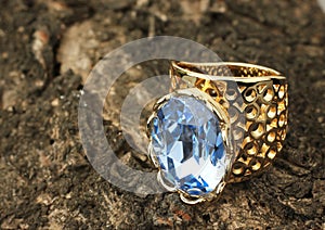 Gold Jewelry ring with blue gemstone on bark of tree