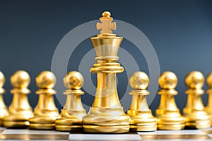 Gold king chess piece stand in front of pawn on black background
