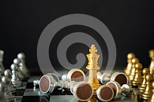 Gold king chess stands on chessboard surrounding with opponents on dark background