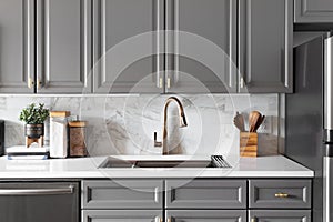 A gold kitchen faucet in a grey kitchen.