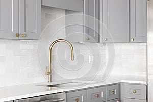 A gold kitchen faucet in a grey kitchen.