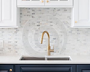 A gold kitchen faucet in a white and blue kitchen.