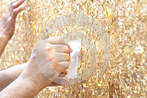 Gold leaf on the wall background. Man hands attach gold leaf