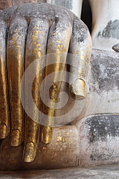 Gold leaves were stuck on the hand of a stone statue of Buddha at Wat Si Chum in Sukhothai (Thailand)