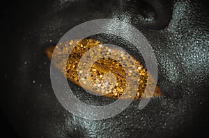 Gold lips with glitter close-up female face on dark background