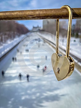 Gold love lock on bridge and skaters on Rideau Canal, Ottawa, Ontario, Canada