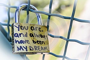 Gold love lock on frence that says Promise and You are and always have been my dream with bokeh background