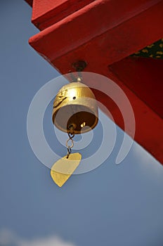 Gold metal handbell or golden steel bell hanging on roof of antique building ubosot church in Wat Bang Phai temple royal monastery