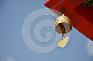 Gold metal handbell or golden steel bell hanging on roof of antique building ubosot church in Wat Bang Phai temple royal monastery