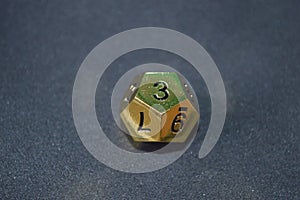 Gold metallic d12 twelve sided dice on foam surface