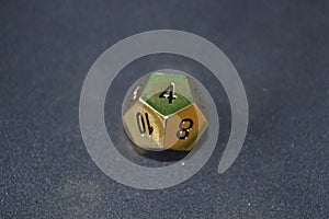 Gold metallic d12 twelve sided dice on foam surface