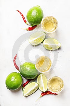 Gold mexican tequila with lime and salt, white drink background, top view