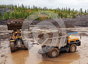 Gold mining industry. A wheel loader loads mountain soil into the back, Mining trucks transport mountain soil