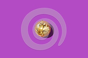 Gold mirror disco ball on violet background. Flat lay, top view. Minimal New year party concept. Christmas greeting card with copy