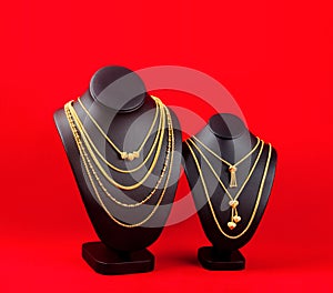 The Gold necklaces on red and black color necklace display stand