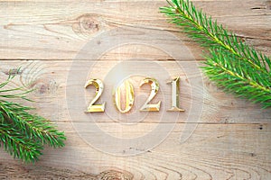 Gold numbers 2021 on a wooden background with Christmas decorations: green branches of spruce, red ball. New Year concept, frame,