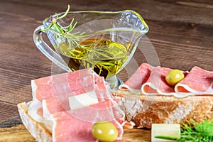 Gold olive oil in the glass transparent bowl, sliced fresh ham and cheese with ham closeup. Healthy food ready to eat