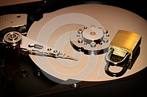 Gold padlock on the opened HDD disk drive surface. Data protection or security concept.