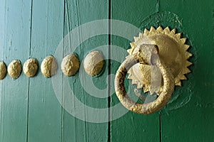 Gold painted doorknocker on a green wooden door