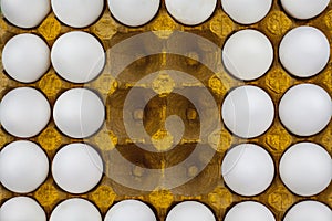 A gold pattern in a cardboard box, surrounded by white eggs, background, texture