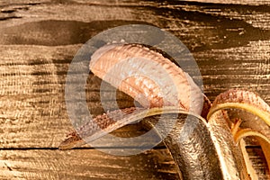 Gold peeled banana on wooden background .