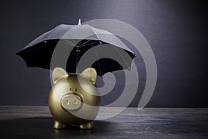 Gold Piggy bank with umbrella concept for finance insurance, protection, safe investment or banking