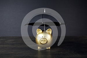 Gold Piggy bank with umbrella concept for finance insurance, protection, safe investment or banking
