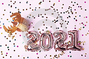 Gold pink balloons in form of numbers 2021. Colorful shiny confetti and christmas bauble deer on pink background. Happy New Year
