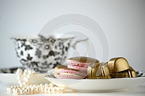 Luxurious gold French macarons and chocolates on a porcelain plate