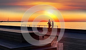 Gold pink sunset at pier summer  sea romantic couple walking relaxing on promenade  wooden tables and bench  on beach Tallinn Esto