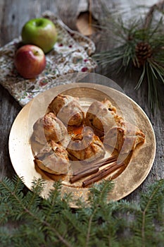 A gold plate of apple dumplings with cinnamon sticks and rustic props