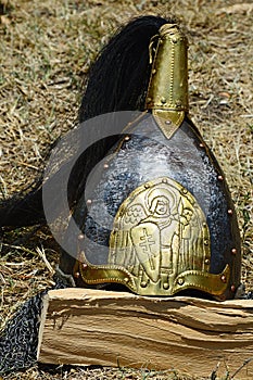 Pozlacená dekorativní středověká kónická přilba s černým hřebínkem do culíku a vyraženými slovanskými křesťanskými motivy