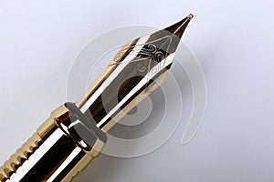 Gold plated fountain pen closeup on a grey background