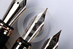 Gold plated fountain pens closeup on a grey background